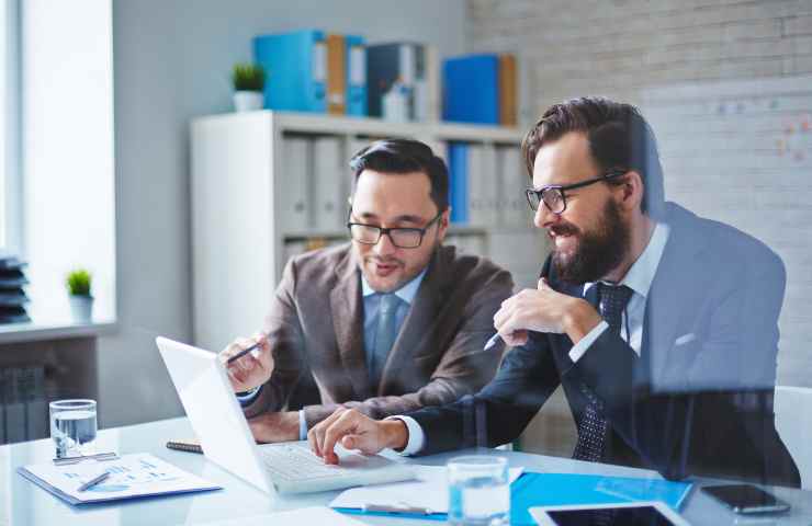 uomini sorridenti consultano pc