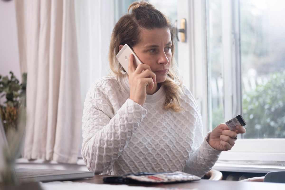 Persona al telefono e una carta di credito in mano