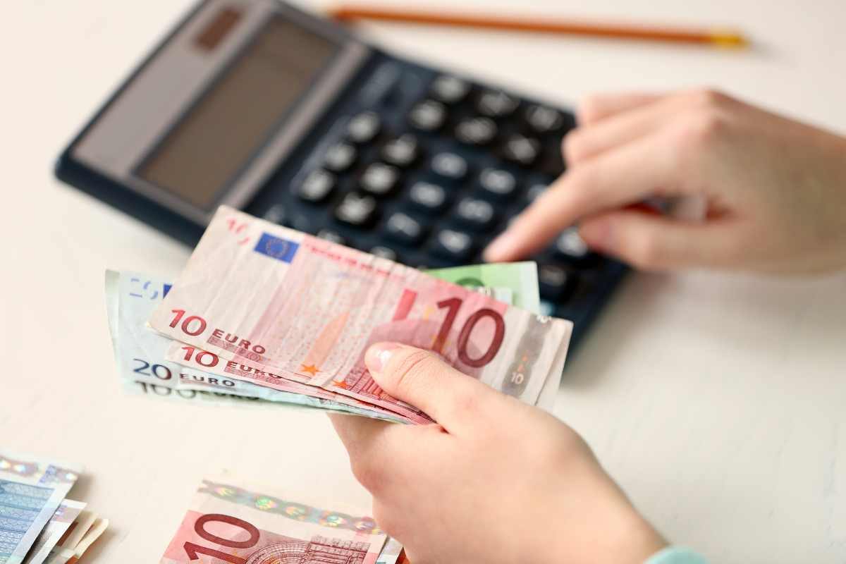 persona con calcolatrice e banconote euro
